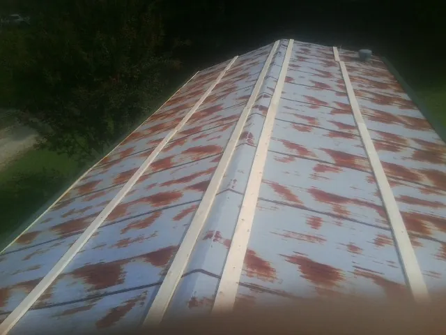 Rusted metal roof panels with new wood purlins before replacement — Storm Damage Roof Repair in Ossian by Roofing Brothers