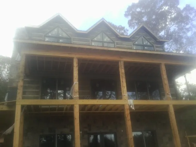 Dormers and porch framing on a large log home under construction — Roof Coating work by our crew in Ossian