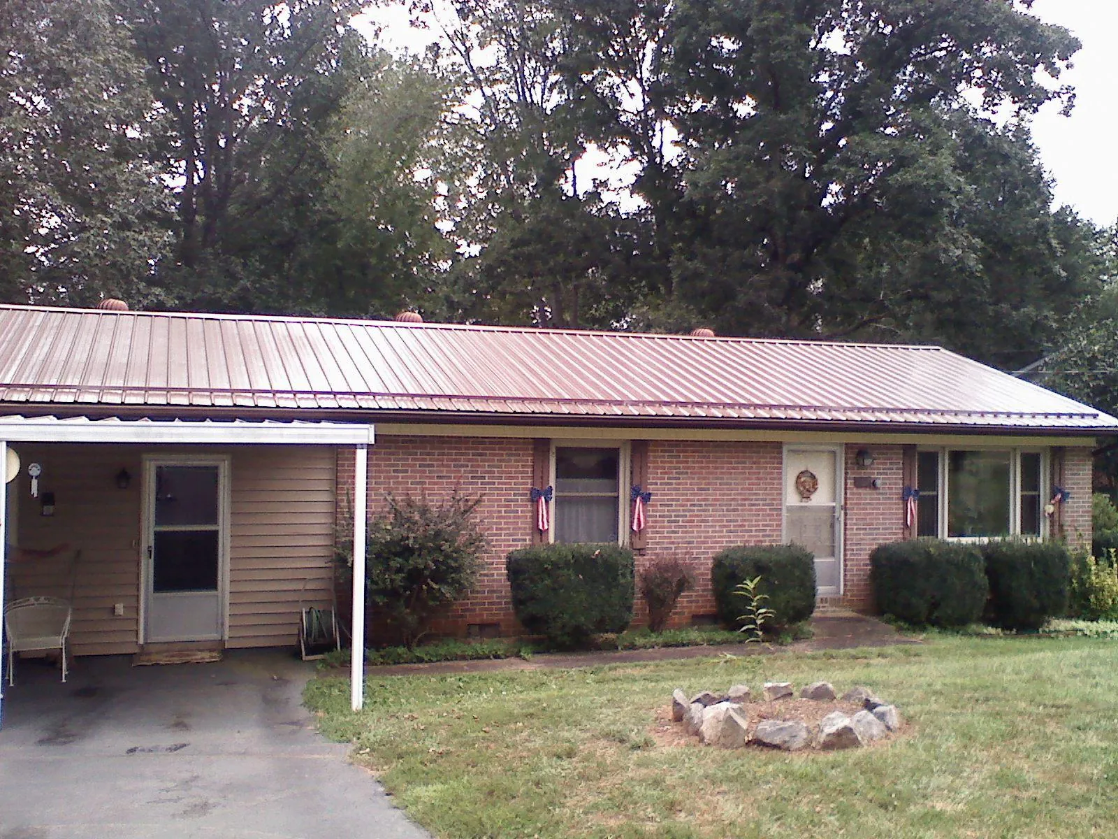 Bronze metal roof and carport on a brick ranch home — Roof Repair work by our crew in Ossian